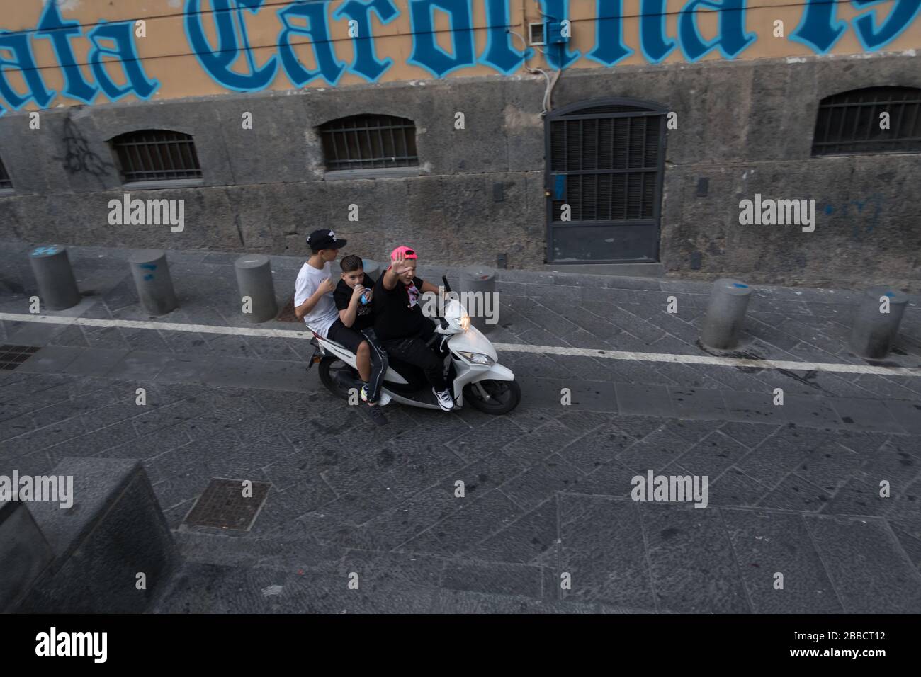 Drei Personen fahren illegal auf einem Roller ohne Helm durch die Straßen  von Neapel Stockfotografie - Alamy
