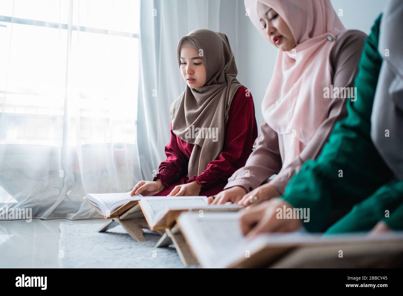 Drei muslimische asiaten lesen und lernen das heilige Buch des Al-Quran zusammen auf dem Boden im Raum sitzen Stockfoto