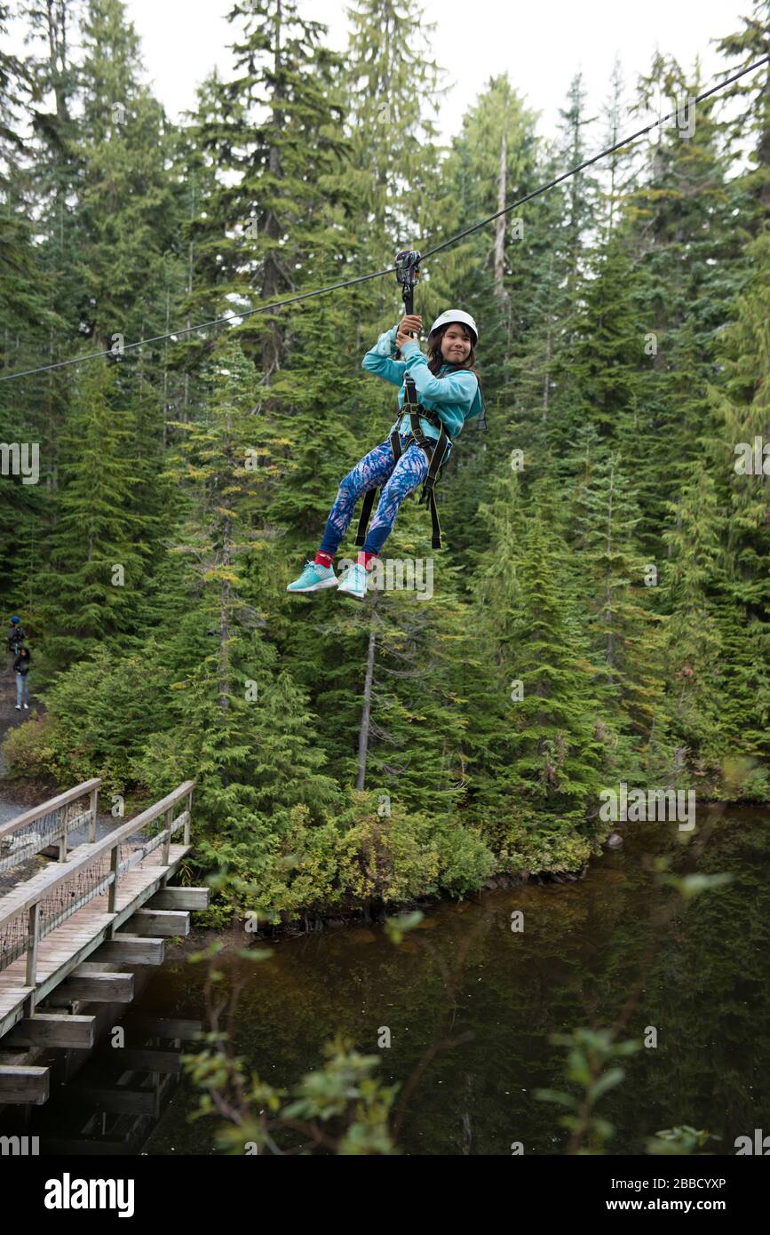 Ein junges Mädchen reitet eine Zipline auf dem Grouse Mountain, North Vancouver, British Columbia, Kanada. Stockfoto
