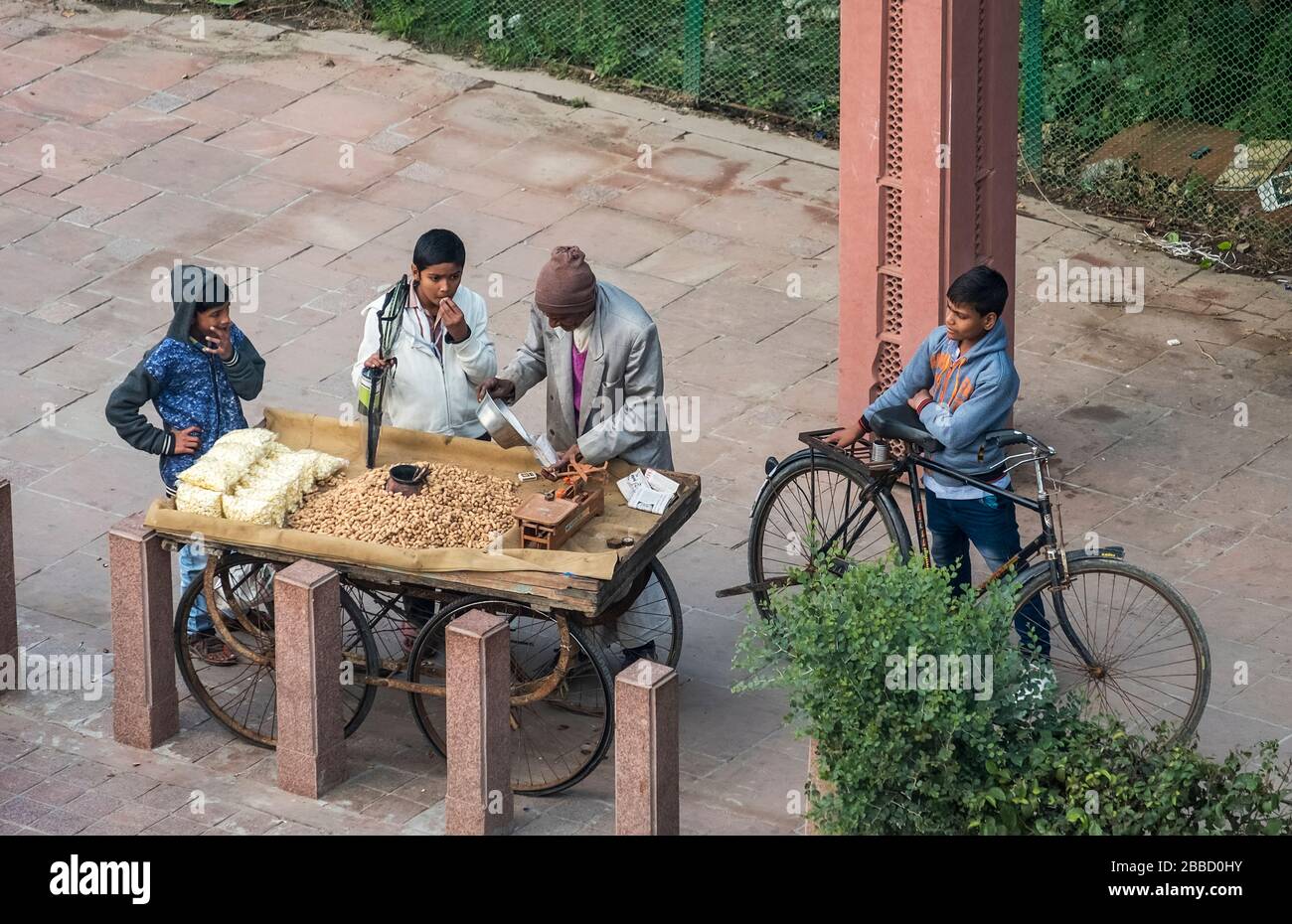 Verkäufer von gerösteten Erdnüssen an einem Straßenrand, der glückliche indische Kinder von seiner Rikscha serviert Stockfoto