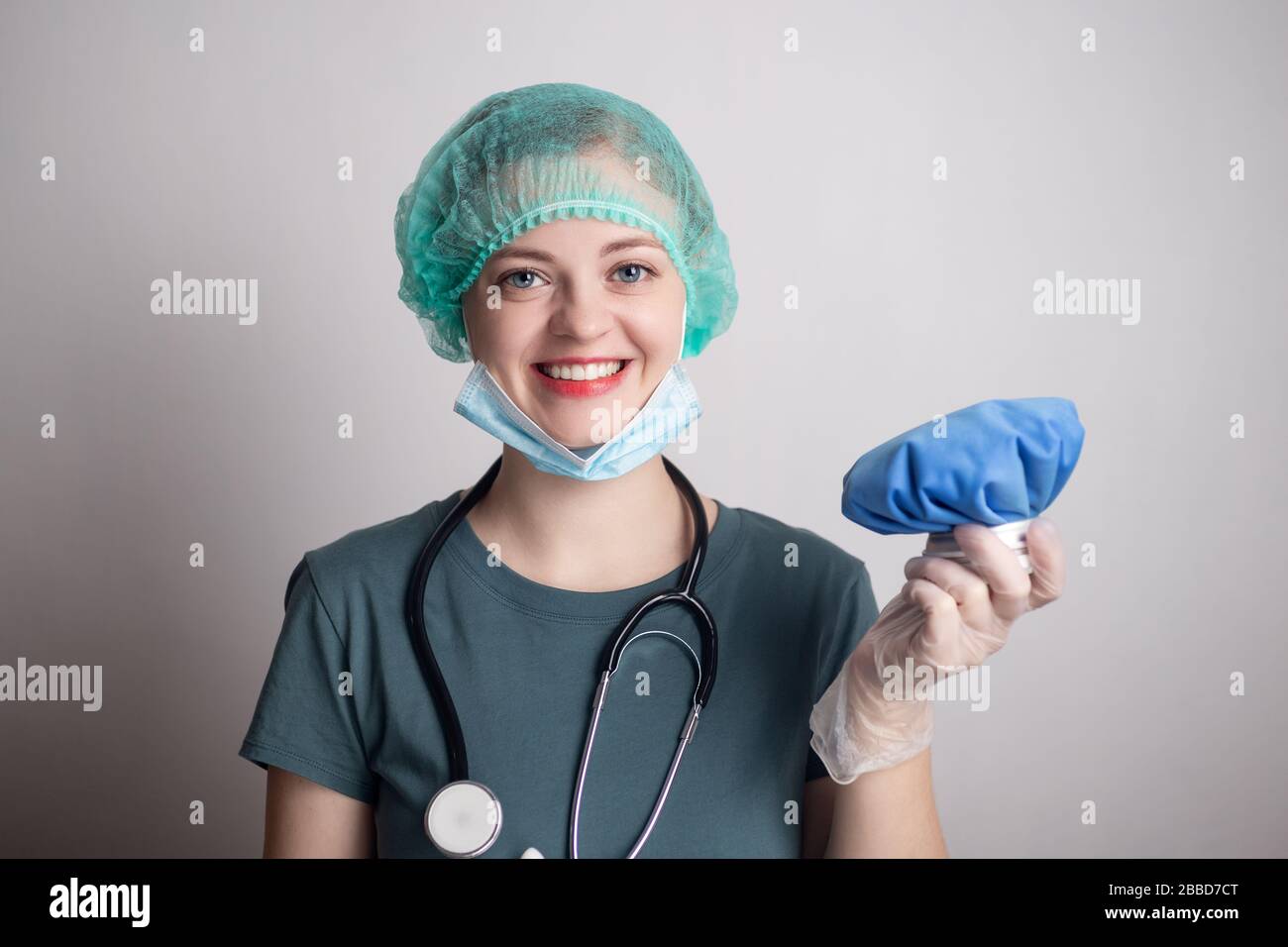 Lächelnde weibliche Ärztin in Uniform mit blauem Eisbeutel Stockfoto