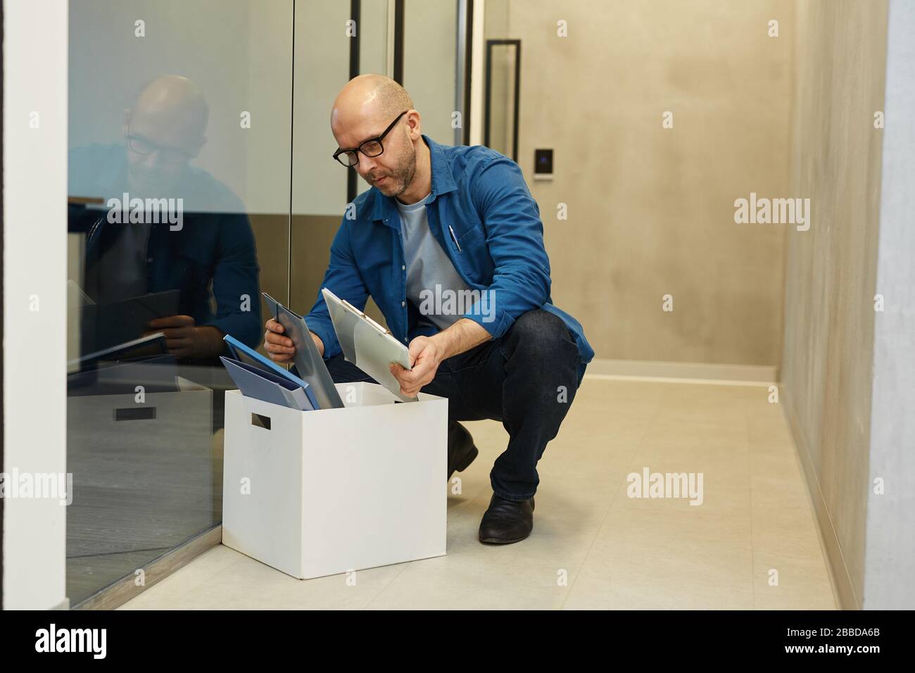 Lange Portrait von Glatze Erwachsene Mann Verpackung mit persönlichen Sachen beim Verlassen des Arbeitsplatzes oder beim Ausziehen, Kopierraum Stockfoto