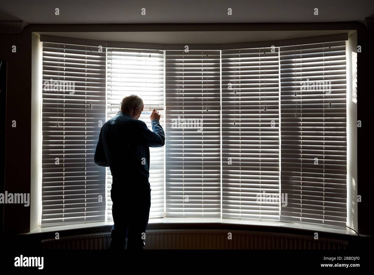 Foto eines Mannes in Schilouette vor einem großen Fenster während der Isolation von UK Covid 19. Stockfoto