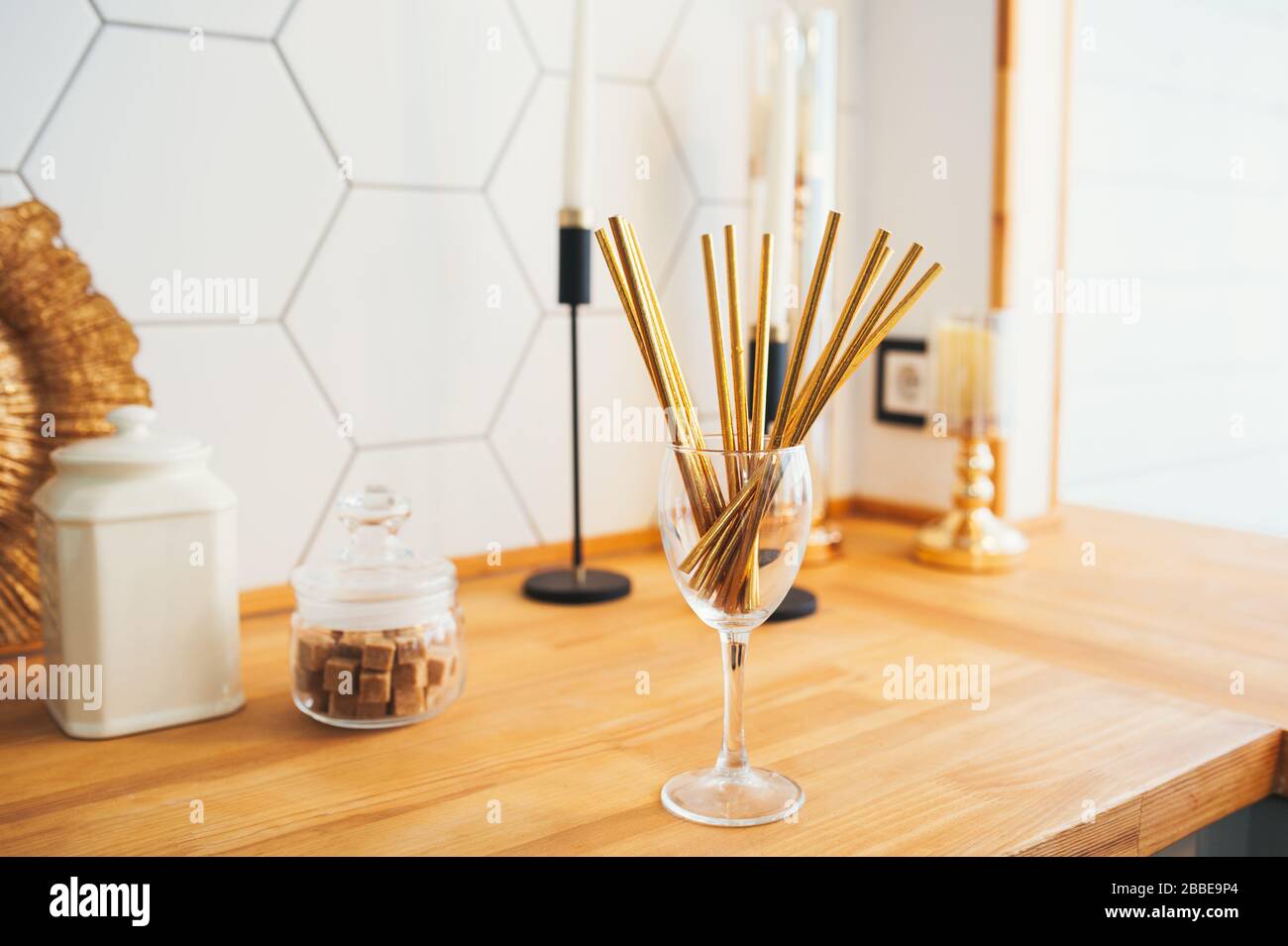 Goldene Papierröhrchen für Getränke aus Glas in einer gemütlichen hellen Holzküche. Stockfoto