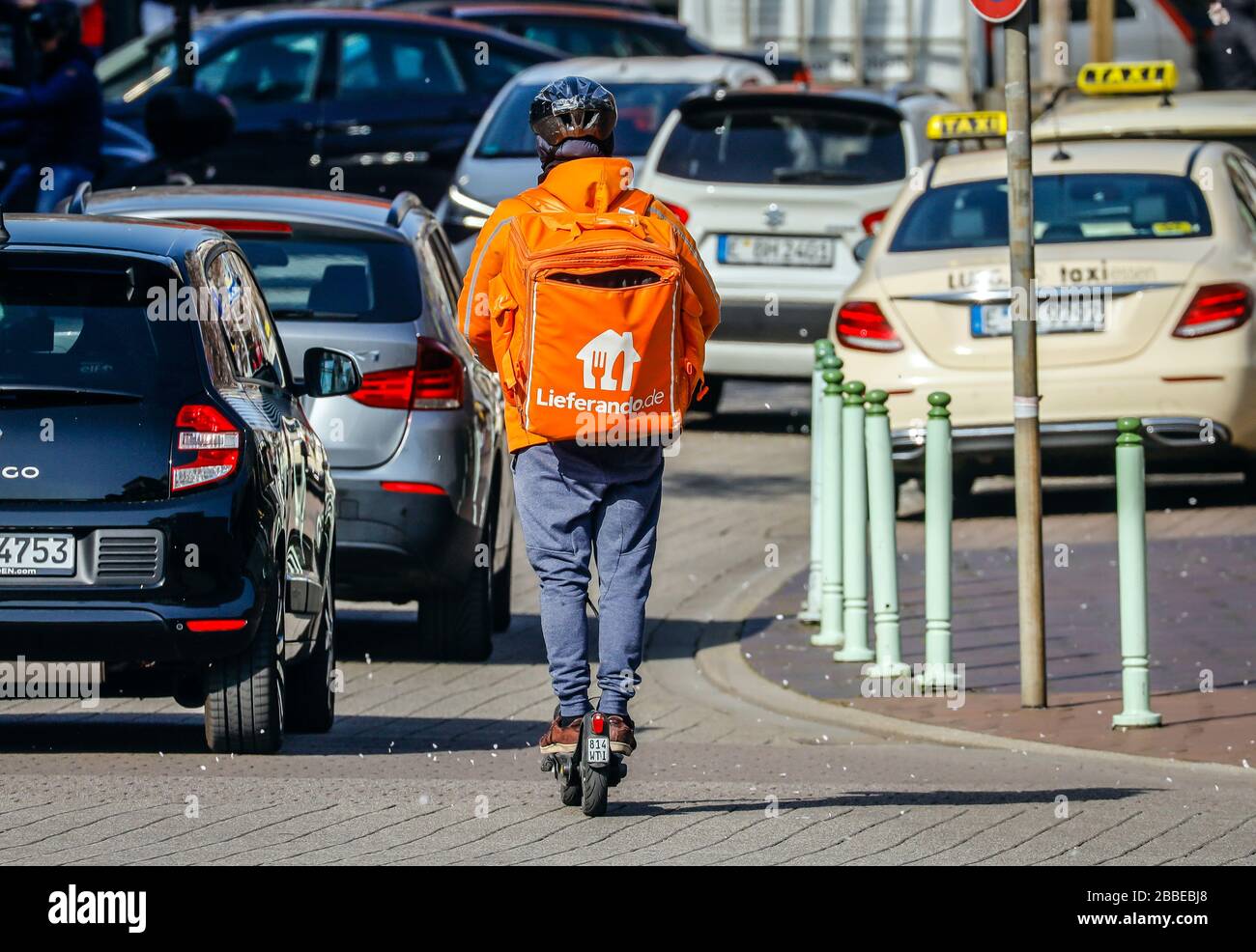 Essen, Ruhrgebiet, Nordrhein-Westfalen, Deutschland - Lieferservice Lieferando, ein Kurierfahrer auf der Straße mit einem Elektroscooter liefert ordre Stockfoto