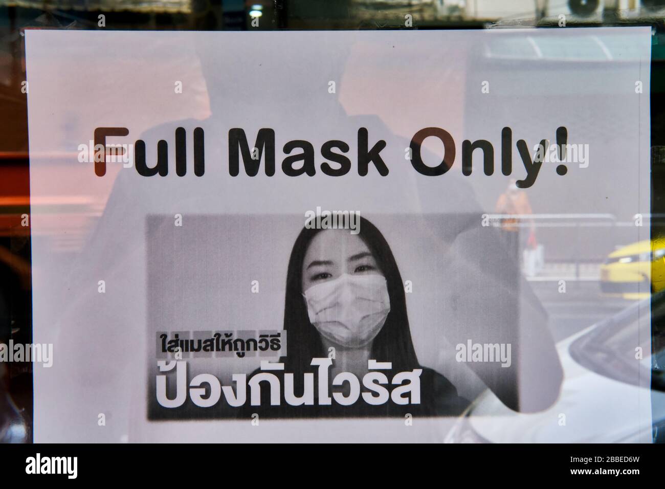Während des Covid-19-Ausbruchs rät eine Notiz an der Tür eines Geldwechslers in Bangkok, Thailand, den Gönnern, mit voller Nase und Mundabdeckung einzudringen Stockfoto