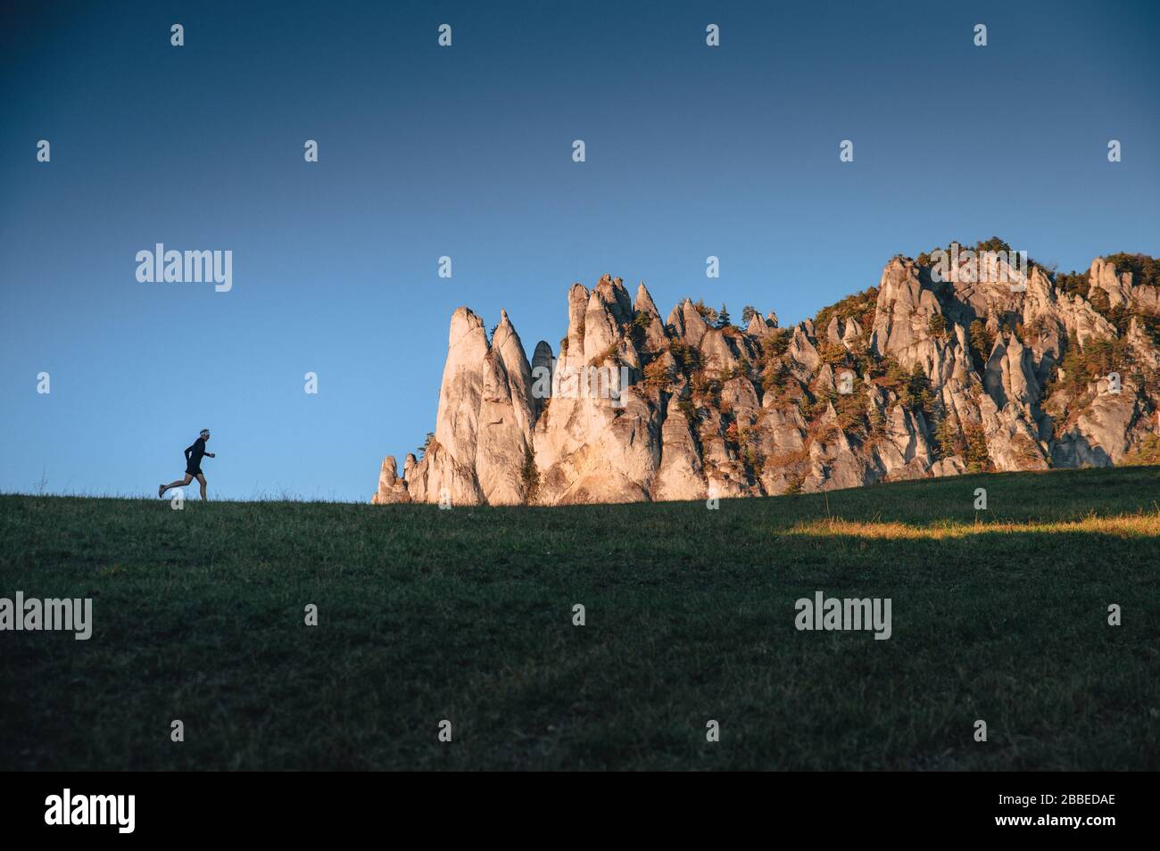 Läufer in ungewöhnlicher Landschaft. Athletensilhouette am Horizont und felsige Hügel im Hintergrund Stockfoto