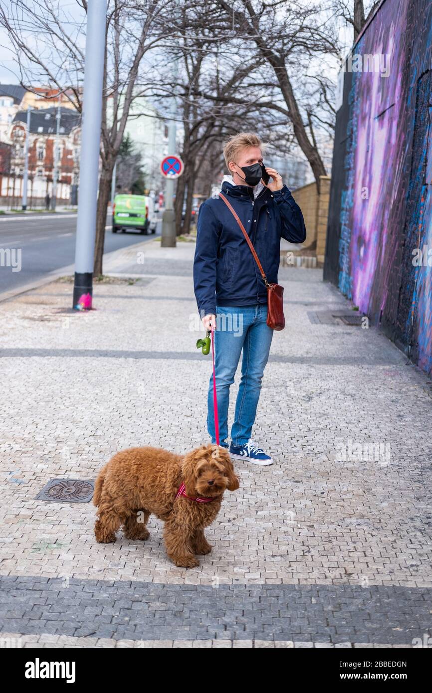 Mann läuft Hund mit Gesichtsmaskenschutz Stockfoto