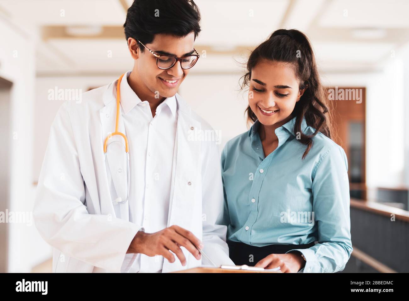 Zwei junge Ärzte diskutieren im Flur in einem Krankenhaus über etwas Stockfoto