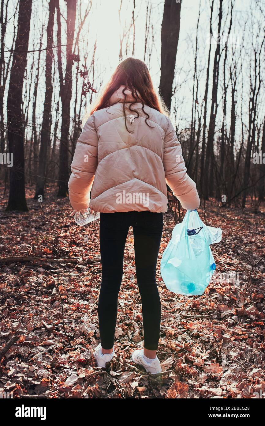 Junge Frau säubert einen Wald. Freiwillige Entnahme von Plastikmüll in Taschen. Konzept der Kunststoffverschmutzung und zu viele Kunststoffabfälle. Umweltbelange Stockfoto