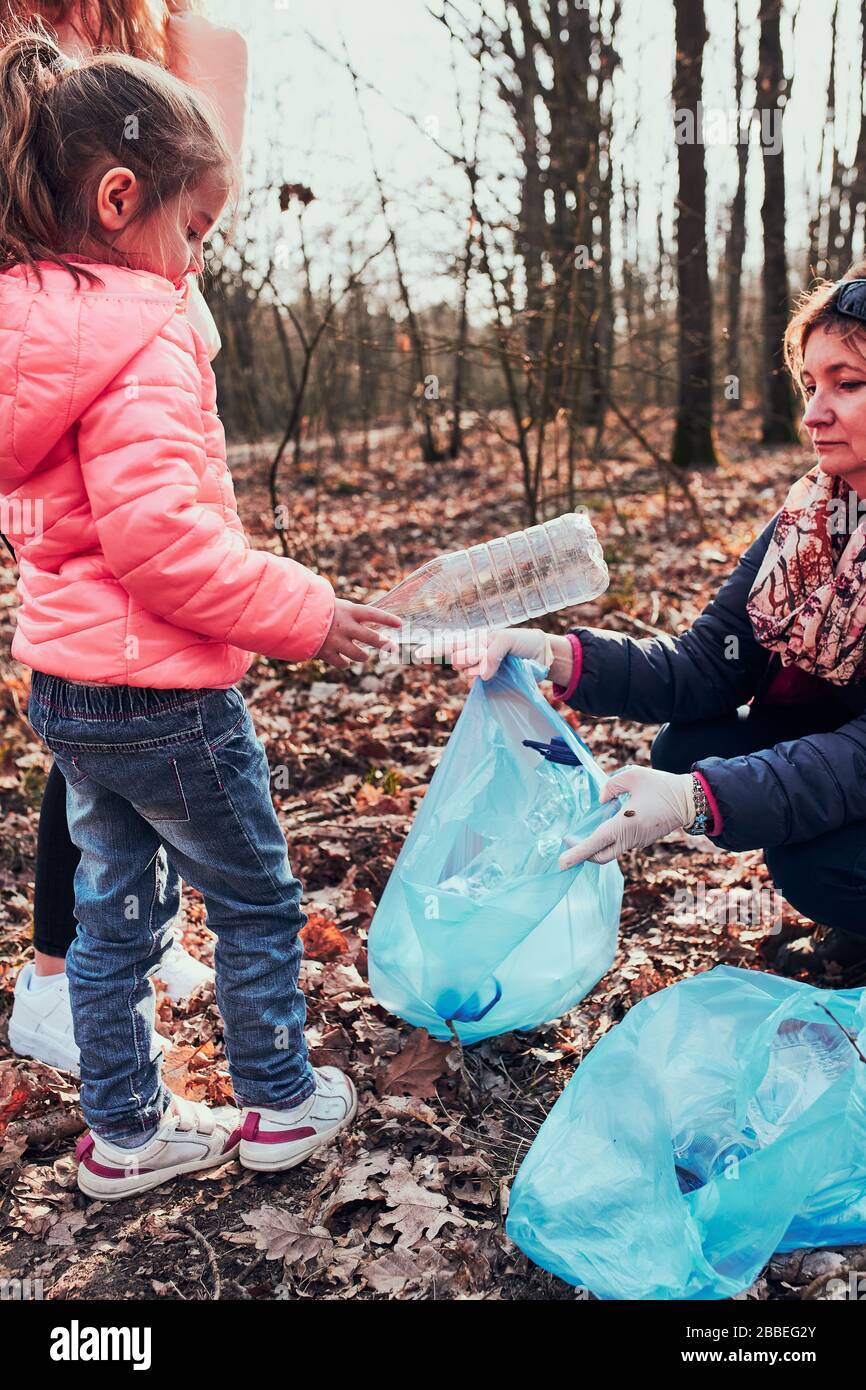 Die Familie säubert einen Wald. Freiwillige, die Plastikmüll in die Tüten holen. Konzept der Kunststoffverschmutzung und zu viele Kunststoffabfälle. Umweltproblem. E Stockfoto