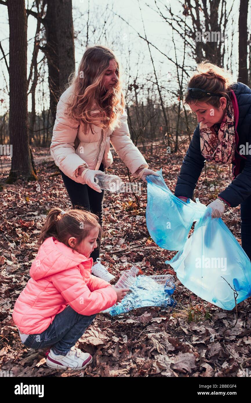 Die Familie säubert einen Wald. Freiwillige, die Plastikmüll in die Tüten holen. Konzept der Kunststoffverschmutzung und zu viele Kunststoffabfälle. Umweltproblem. E Stockfoto