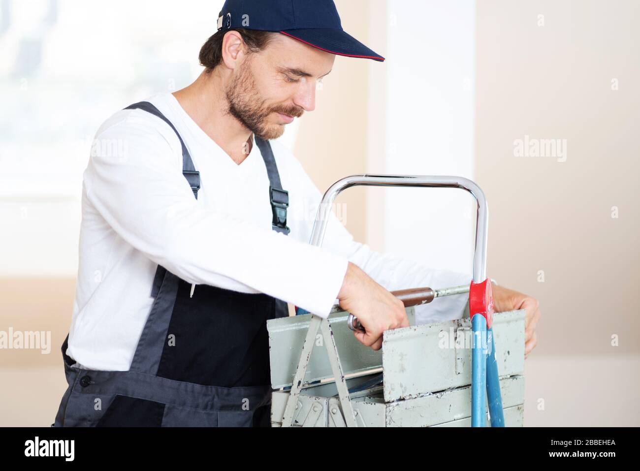 Attraktiver, freundlich lächelnder Handwerker in Arbeitskleidung und mit Werkzeug Stockfoto