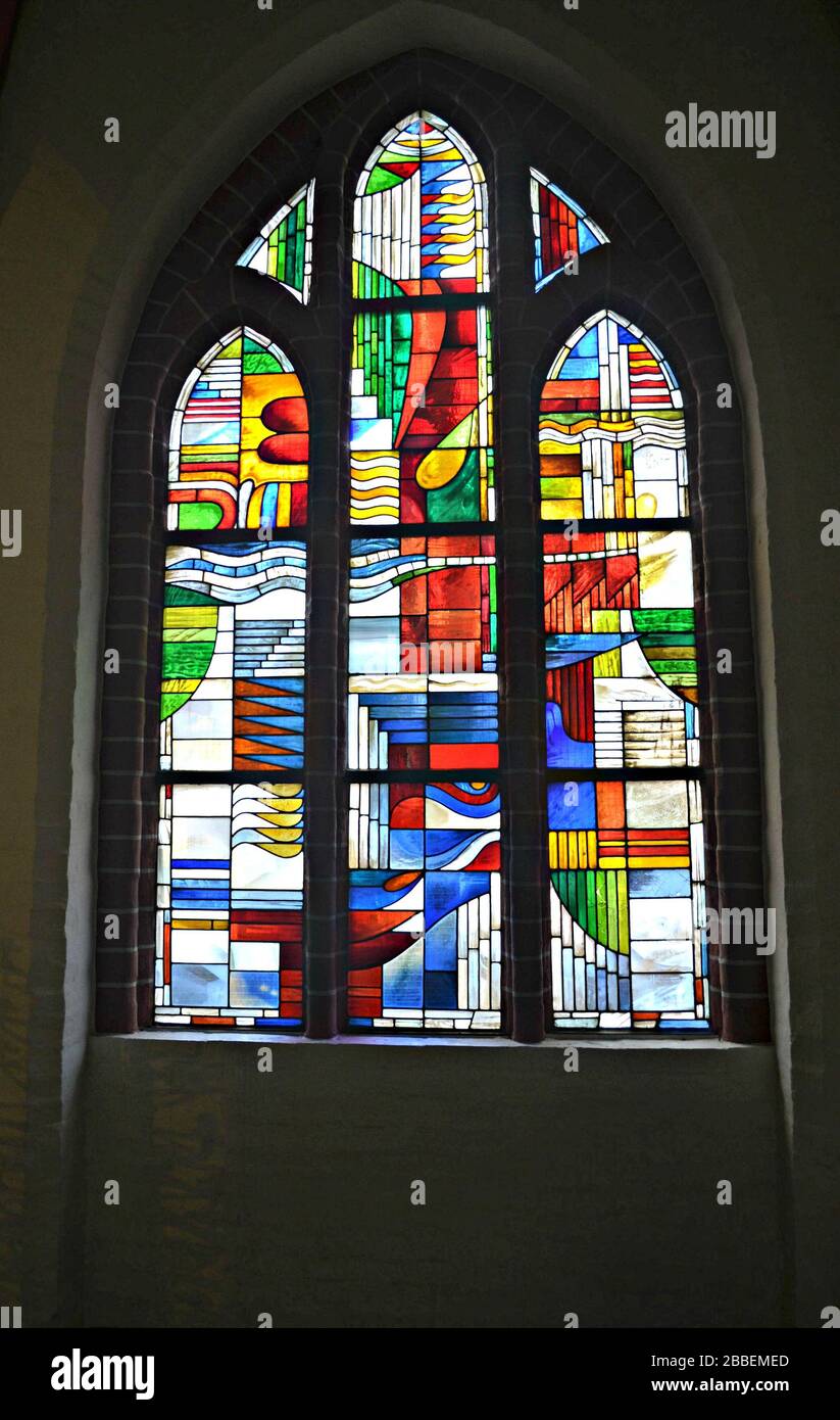 Buntes Buntglasfenster und großer Kerzenständer in der St. Johannes Kirche in Lüneburg Stockfoto