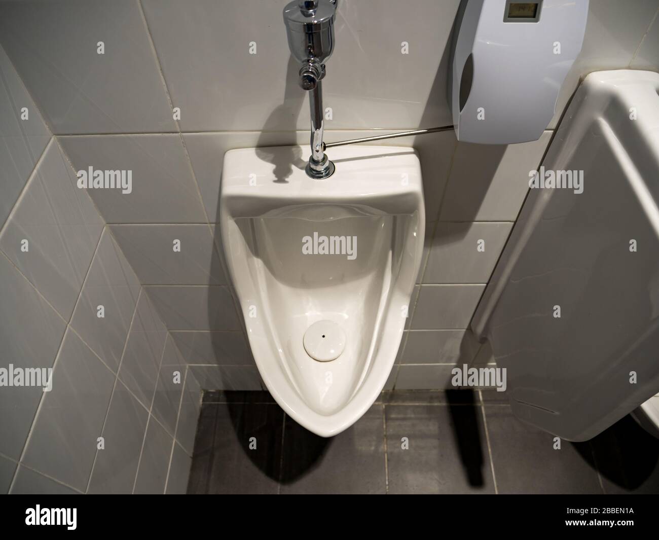 Hochwinkeliger Blick auf ein weißes Porzellan Herrenurinal in einer sauberen öffentlichen toilette für Männer Stockfoto