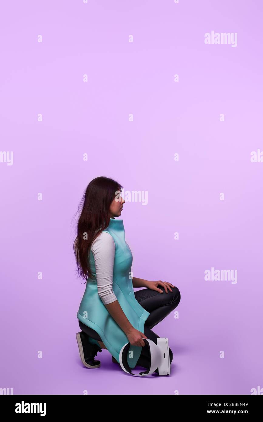 Frau mit Headset für virtuelle Realität in ihren Händen. Konzept der virtuellen Realität, Spiele, Unterhaltung und Kommunikation. Stockfoto
