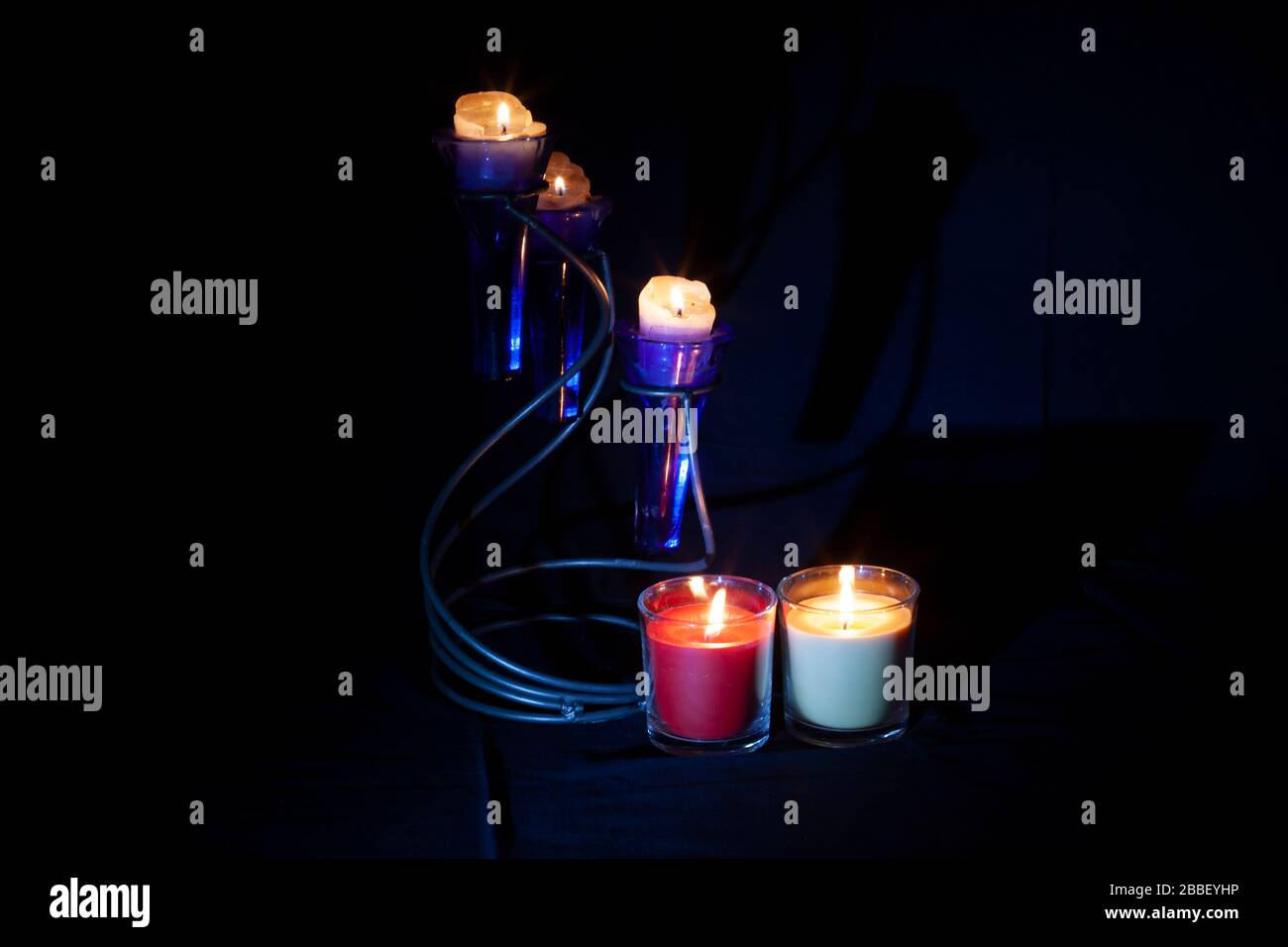Lite Kerzen vor schwarzem Hintergrund mit Kerzenlicht und einer kleinen Fackel, Northampton, England, Großbritannien. Stockfoto