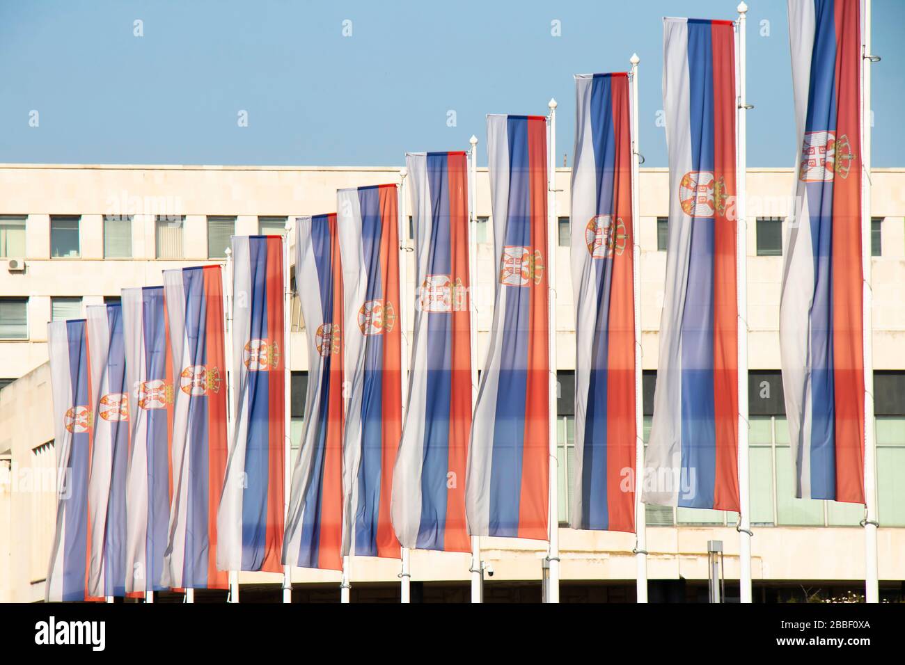 Belgrad, Serbien - 20. März 2020: Serbische Nationalflaggen auf Pfosten vor dem Palast von Serbien, einem Regierungsgebäude in New Belgrad Stockfoto