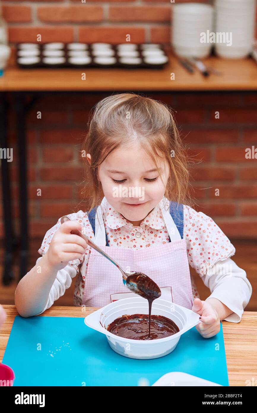Kleiner Koch, der heiße geschmolzene Schokolade mit Kakao mischt. Kind ...