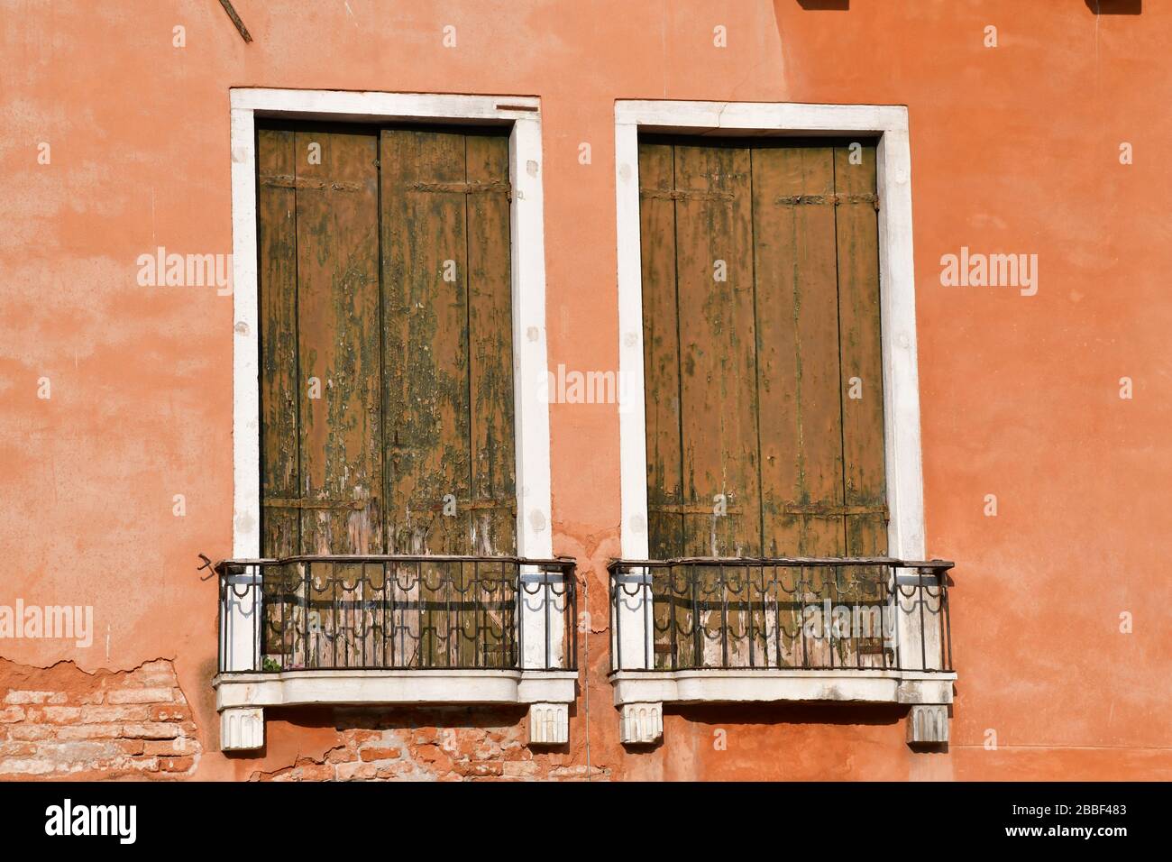 Nahansicht des Fensterabschnitts eines der historischen Gebäude in Venedig; Blenden deutlich verwittert und Wand etwas verblasst Stockfoto