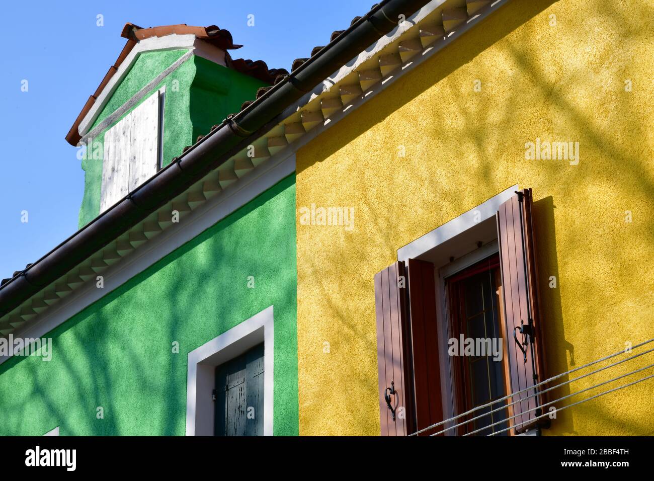 Venedig, Italy-Februar 2020; Nahaufnahme eines Abschnitts eines der alten Gebäude in Burano in der Nähe von Venedig mit bunter Fassade in Grün und Gelb Stockfoto