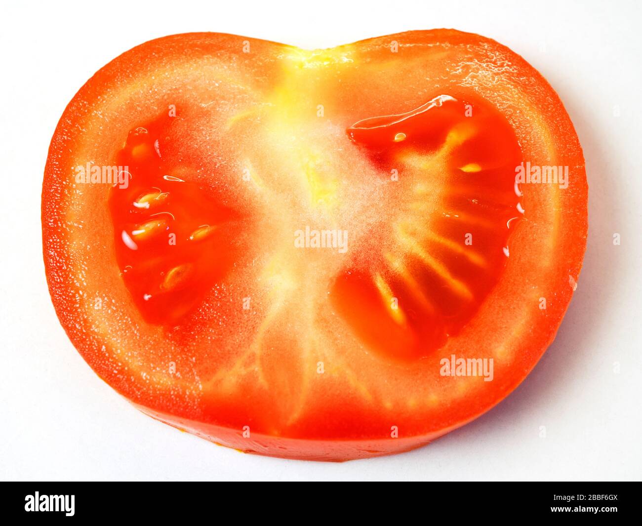 Eine einzelne reife rote Tomatenscheibe auf weißem Hintergrund Stockfoto