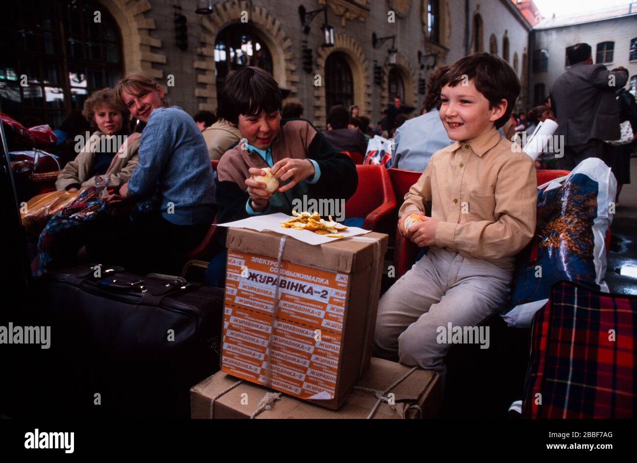 Jungen essen Orangen, während sie mit anderen Passagieren an einem Moskauer Bahnhof warten, Mai 1990. Stockfoto