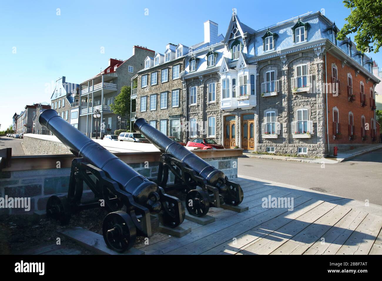 Zwei Canons, die über einer Öffnung in der nördlich gelegenen Befestigungsanlage der Altstadt von Quebec positioniert sind. Am Rande der Befestigungsanlage verläuft die Rue des Remparts und eine Reihe gehobener Steinwohnungen. Oberstadt, Quebec City, Provinz Quebec, Kanada Stockfoto