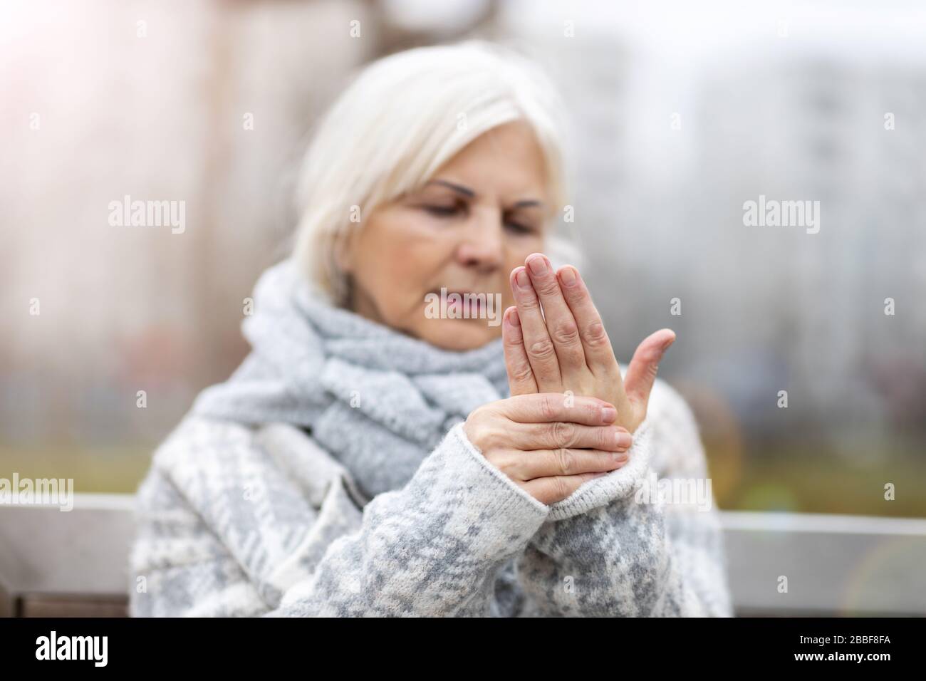 Ältere Frau mit reibenden Händen der Arthritis Stockfoto