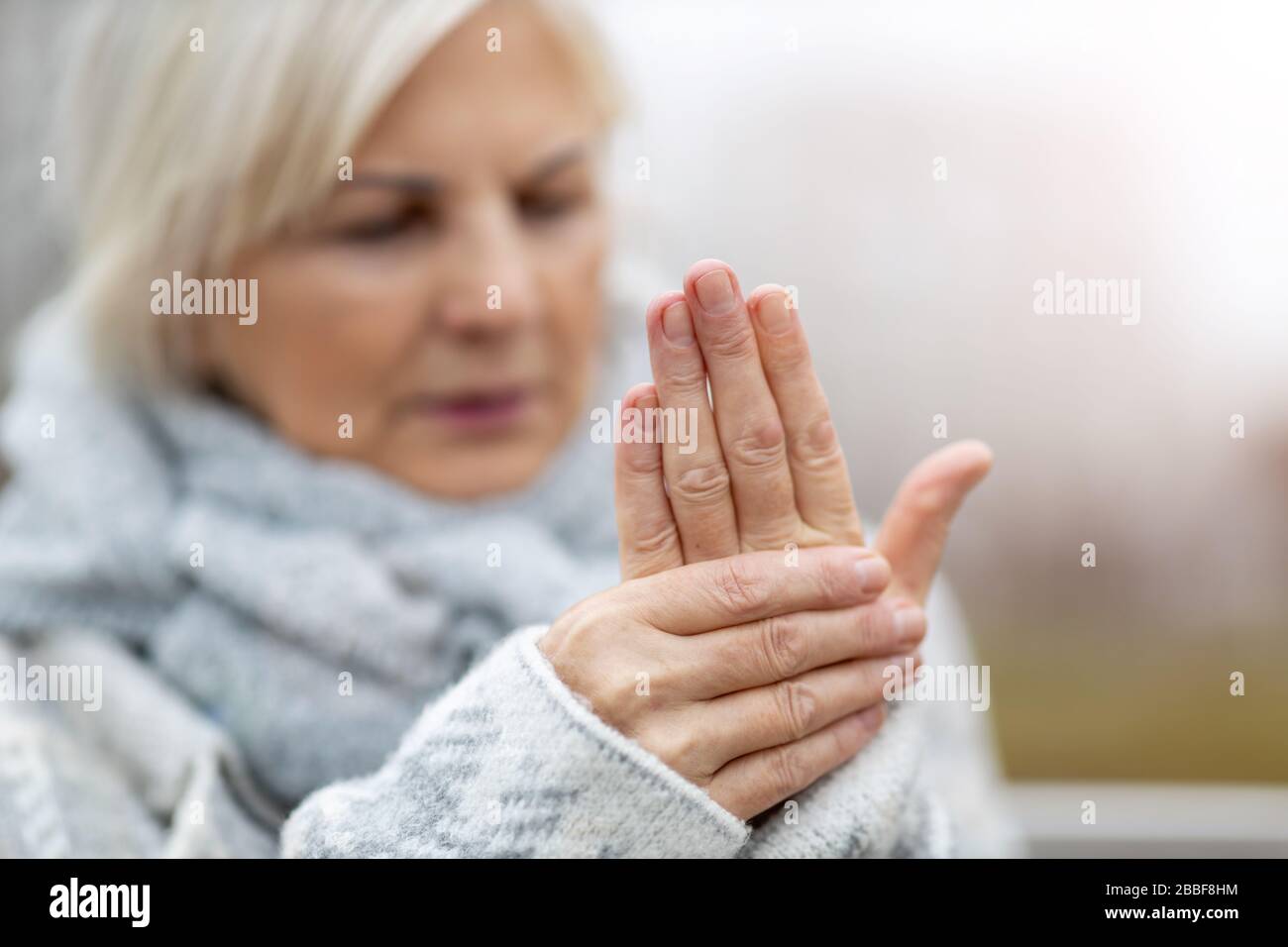 Ältere Frau mit reibenden Händen der Arthritis Stockfoto