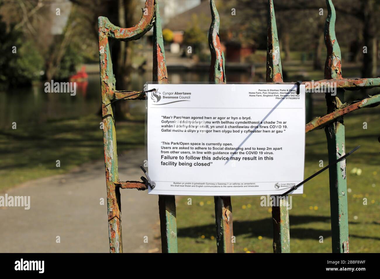 Coronavirus Covid 19 Schild mit sozialer Distanzierung auf einem Parktor Stockfoto