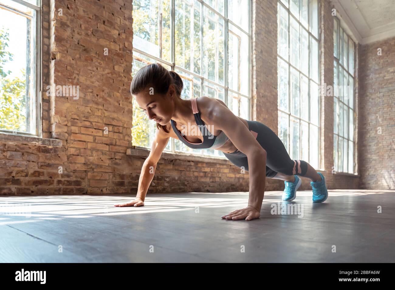 Fit sportliche Frau tragen Sportbekleidung in Plankenstellung im Fitnessstudio auf Holzboden. Stockfoto