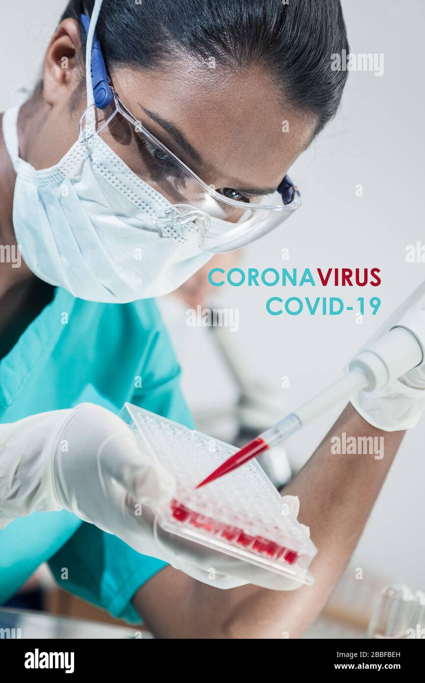 Forscherin oder Ärztin der asiatischen indischen Medizinerin, die eine Gesichtsmaske trägt, die Coronavirus COVID-19 Blutprobe in einem Labor mit ihrer Koll testet Stockfoto