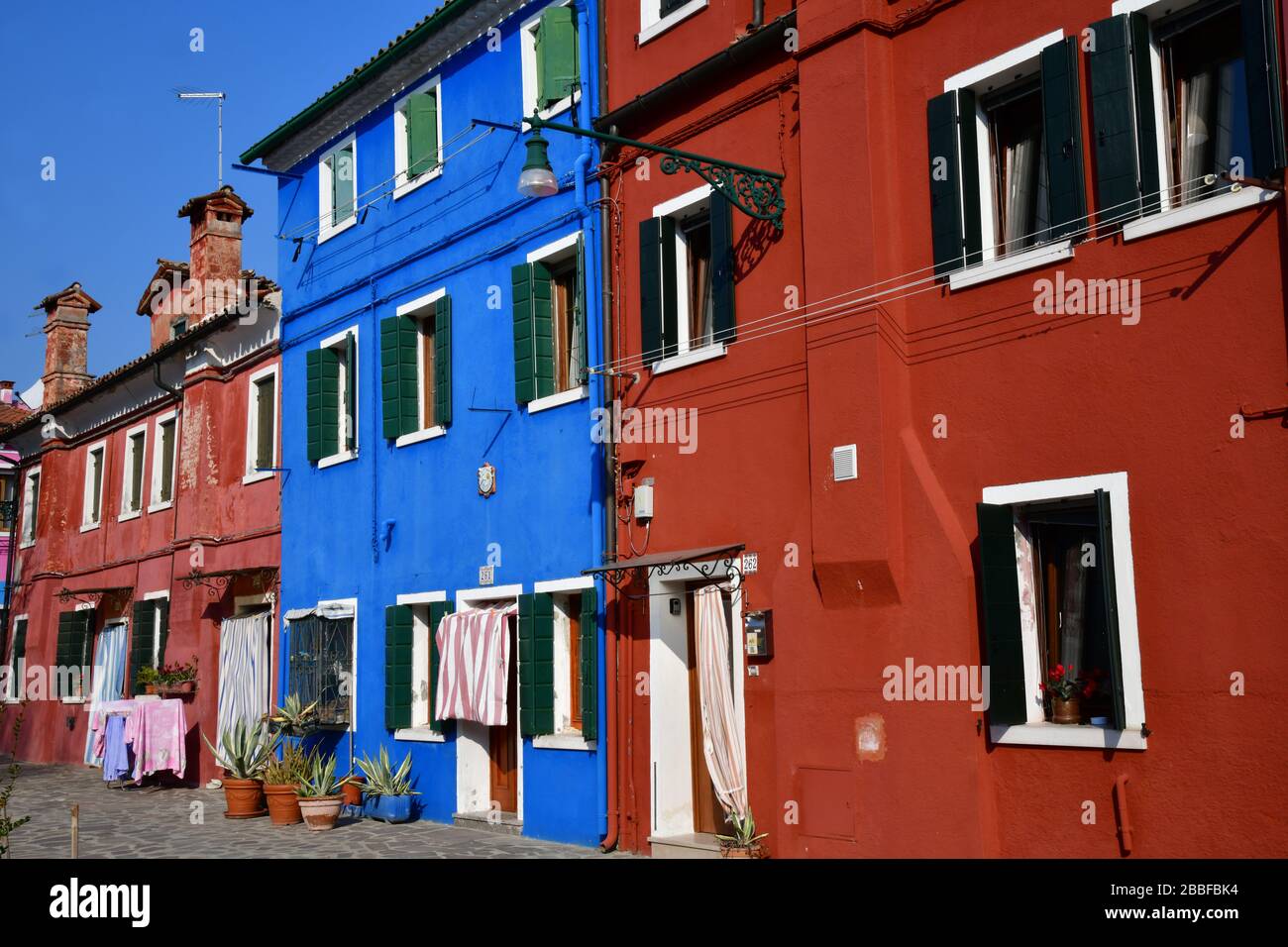 Blick auf einige der farbenfrohen Häuser in Burano an einem sonnigen Tag mit hellblauem Himmel Stockfoto