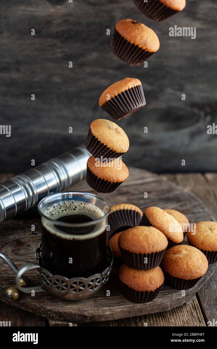 Fliegende Muffins fallen in eine Tasse Kaffee. Fliegende Lebensmittel. Stockfoto