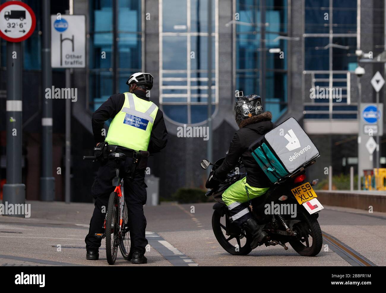 Birmingham, West Midlands, Großbritannien. März 2020. Ein Fahrer von Deliveroo passiert einen Polizei-Community-Support-Officer in der Innenstadt von Birmingham während der Pandemie-Sperre von Coronavirus. Credit Darren Staples/Alamy Live News. Stockfoto