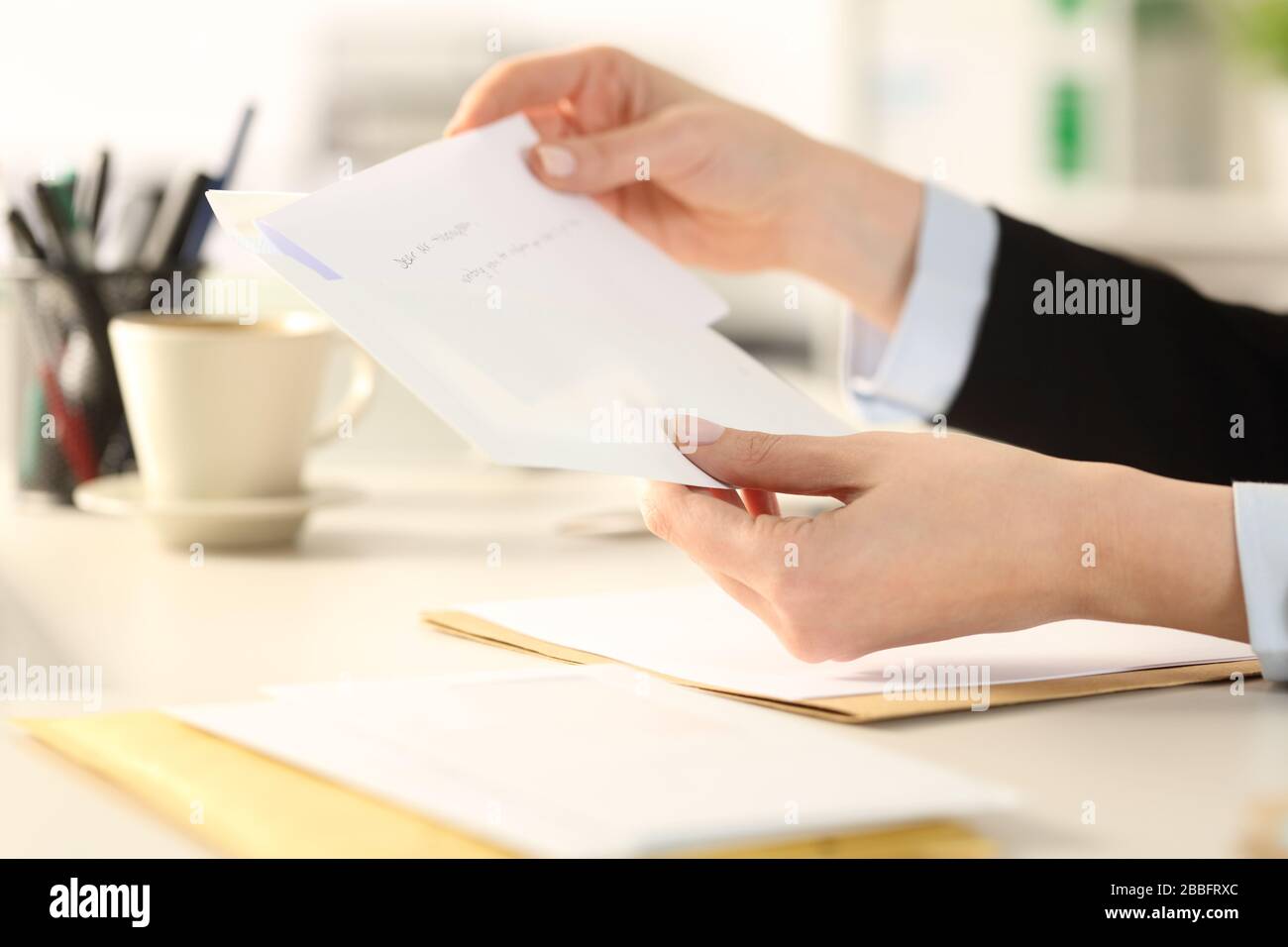 Nahaufnahme der Geschäftsfrau, die einen Brief auf einen Umschlag legt, der auf einem Schreibtisch im Büro sitzt Stockfoto