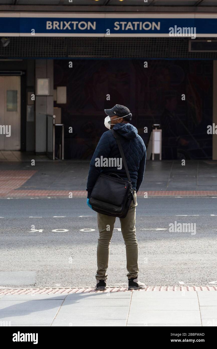 Mann mit Gesichtsschutzmaske und Handschuhen außerhalb der Brixton Station, während der Londoner Sperre aufgrund der Ausbreitung von Covid-19. Am 31. März 2020 aufgenommen Stockfoto