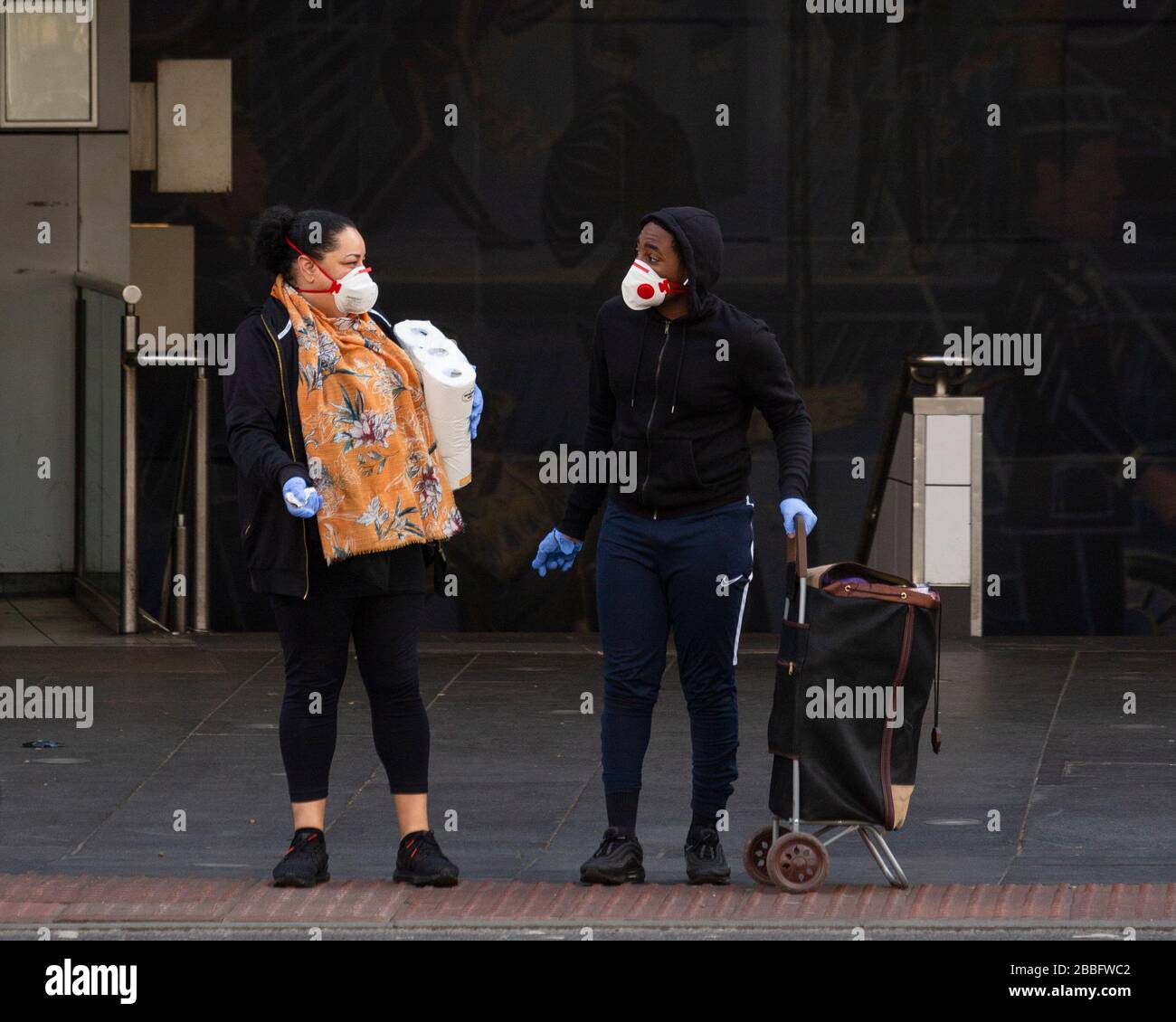 Ein Mann und eine Frau, die vor der Brixton Station stehende Gesichtsmasken und Handschuhe tragen, während der Londoner Sperre aufgrund der Ausbreitung von Covid-19. Genommen Stockfoto