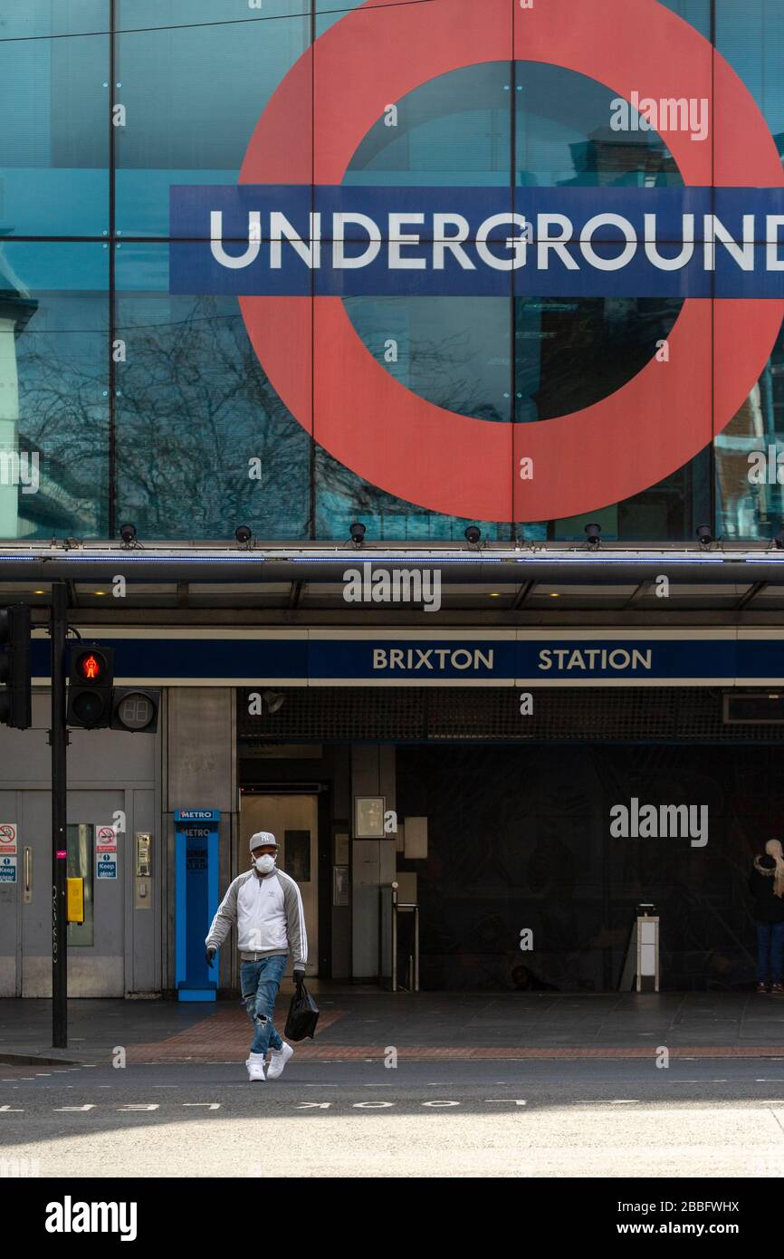 Mann mit Gesichtsschutzmaske außerhalb der Brixton Station, während der Londoner Sperrung aufgrund der Ausbreitung von Covid-19. Am 31. März 2020 aufgenommen Stockfoto
