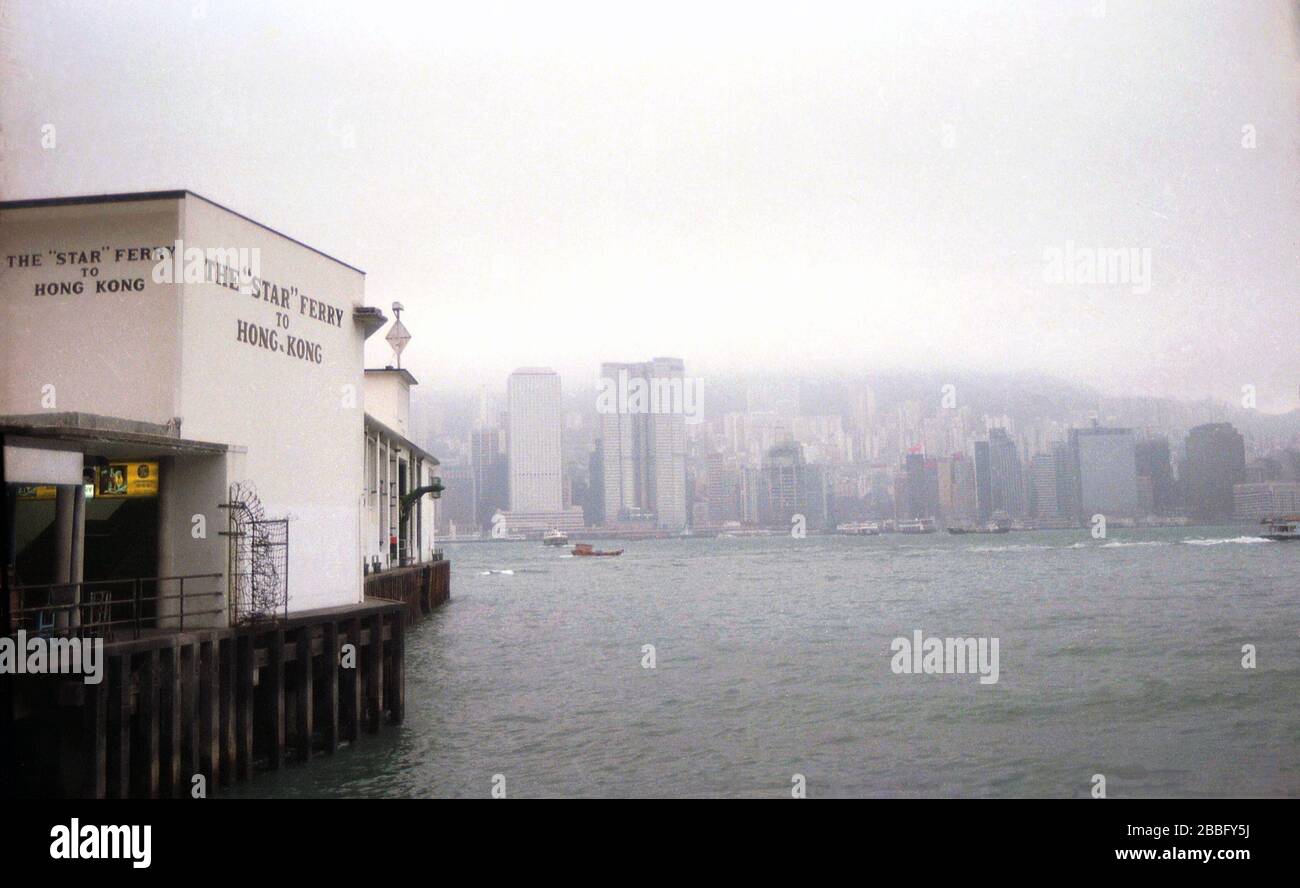 1970, historisch, Kowloon, Hong Kong, der Fähranleger oder Terminal der „Star“-Fähre nach Hong Kong, mit der Skyline von Hong Kong Insel in der Ferne über die Gewässer des Victoria Hafens gesehen. Der Fährenterminal ist ein Pier, der sich auf dem zurückreklamierten Land am Rand von Tsim Sha Tsui auf Kowloon befindet. Stockfoto