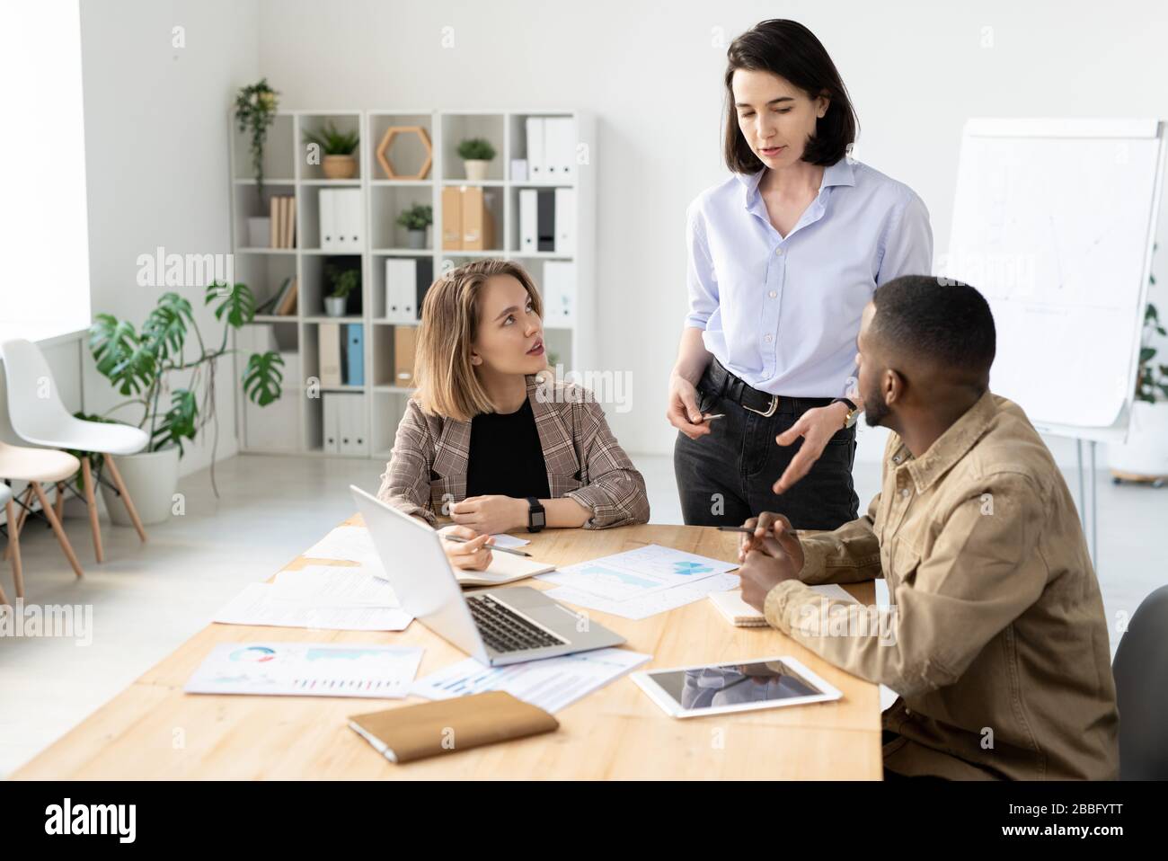 Junge multiethnische Kollegen diskutieren analytische Daten, während sie an einer neuen Werbekampagne arbeiten Stockfoto