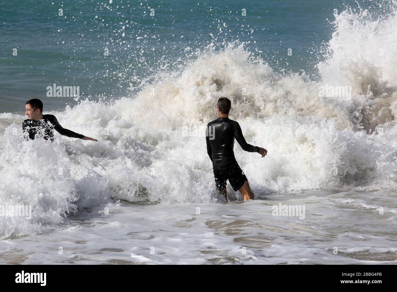 Grand Anse Beach Grenada Männer im Meer haben beim Brechen von Wellen aufgefangen Stockfoto