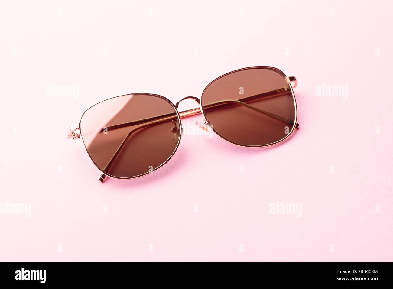 Classic Aviator Spiegel-Sonnenbrille mit goldenem Metallrahmen im Nahaufnahme auf pinkfarbenem Hintergrund, Draufsicht Stockfoto