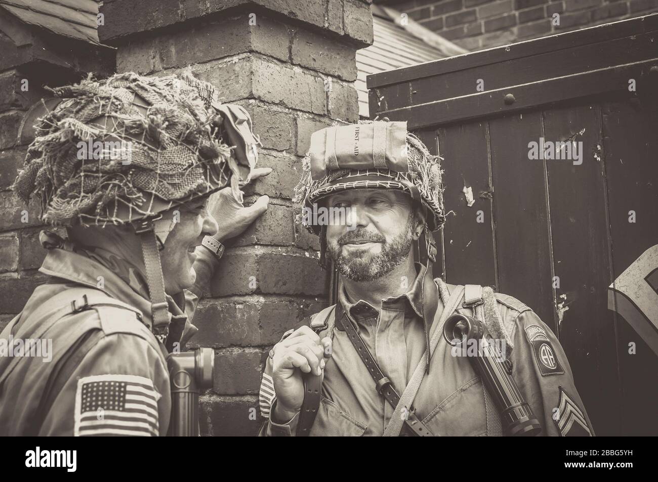 Freunde lächeln, junge Männer miteinander in Kostümen als amerikanische US-Soldaten plaudern, Sommerveranstaltung der 1940er Jahre, Black Country Living Museum, Großbritannien. Stockfoto