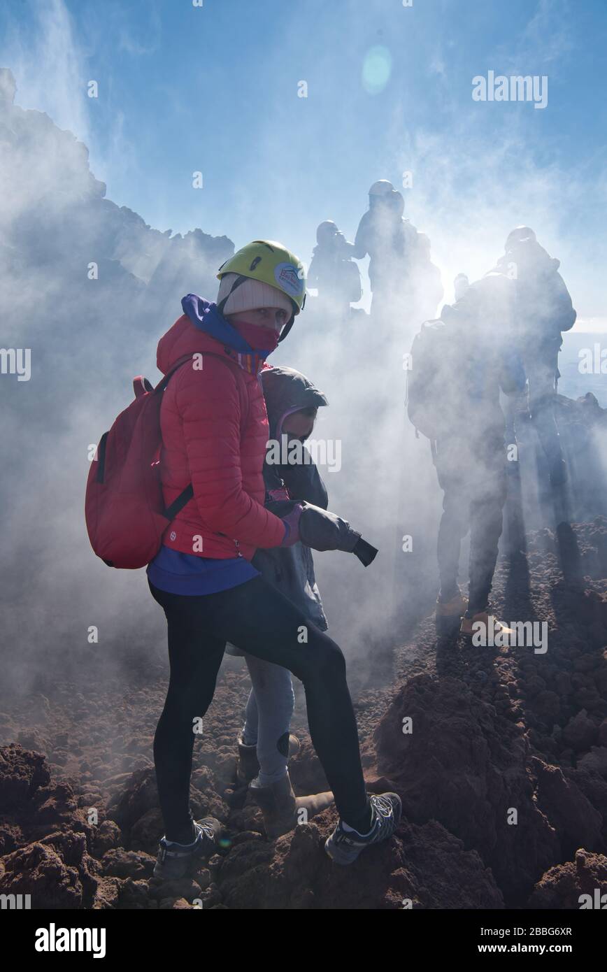Wasserdampf und andere vulkanische Gase überlaufen die Gipfelkrater des Ätna und schütten sich über die oberen Hänge des Vulkans aus. Die Menschen verschwinden im Dampf. Stockfoto