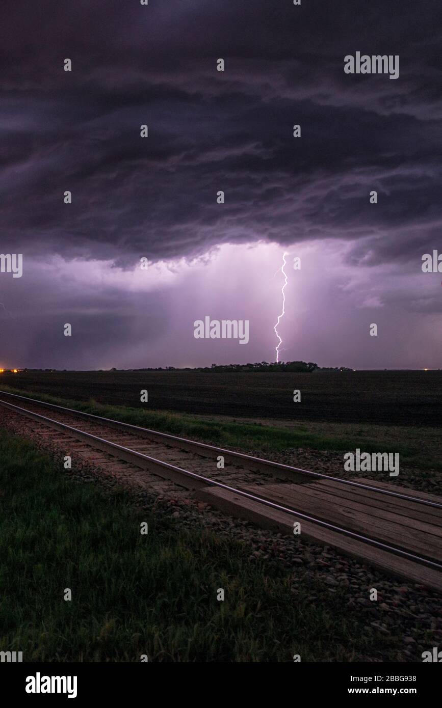 Sturm mit blitzblitzendem Bahnübergang und Bahngleisen im Süden Manitobas Kanadas Stockfoto