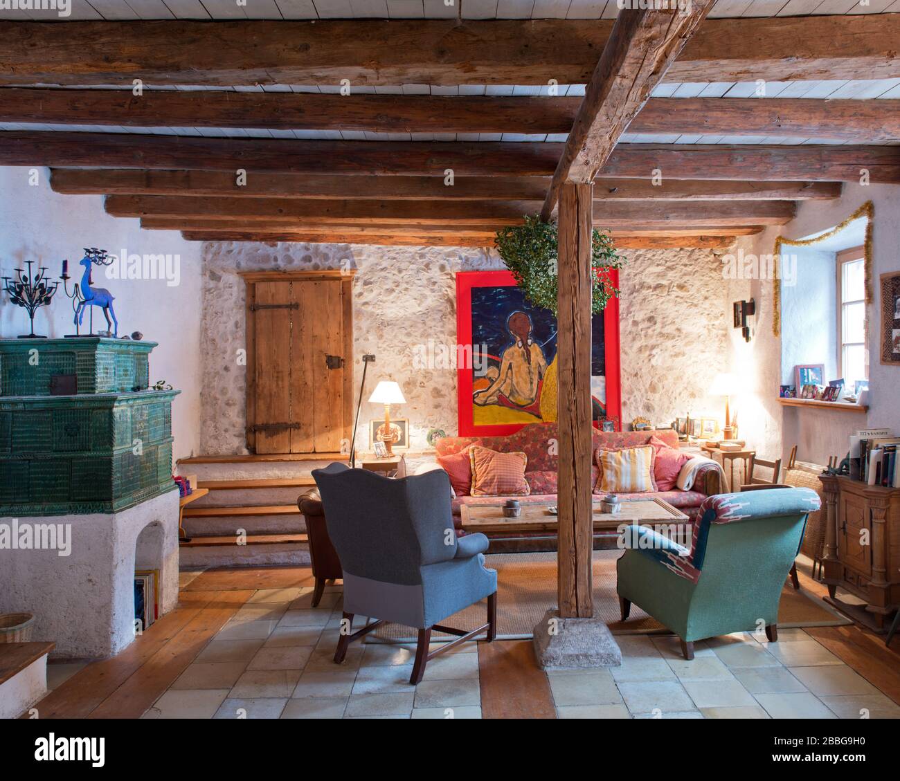 Wohnzimmer im Landhausstil mit grünem Kachelofen, Sofa, Holztramen und Ölgemälde Stockfoto