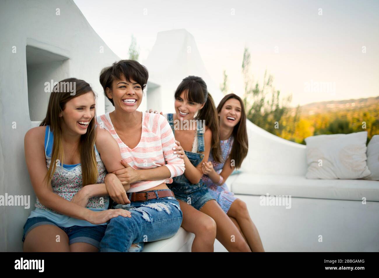 Vier lächelnde Freunde sitzen auf einem Balkon Stockfoto