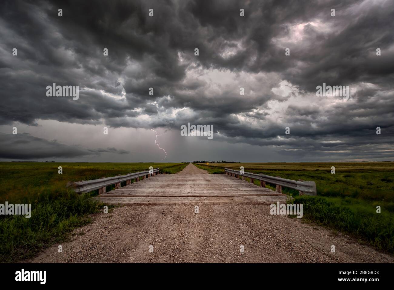 Sturm mit Blitzschlag über alte Landbrücke auf Schotterstraße im ländlichen Süden Manitobas Kanadas Stockfoto